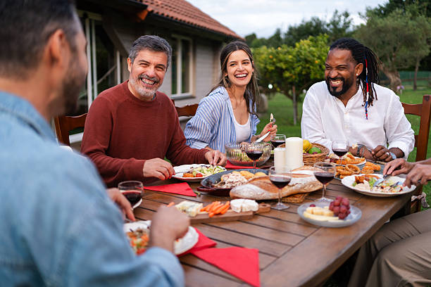 istock Multicultural friends sharing hearty laughter while dining together, surrounded by lush greenery in sunny backyard environment 2226379666