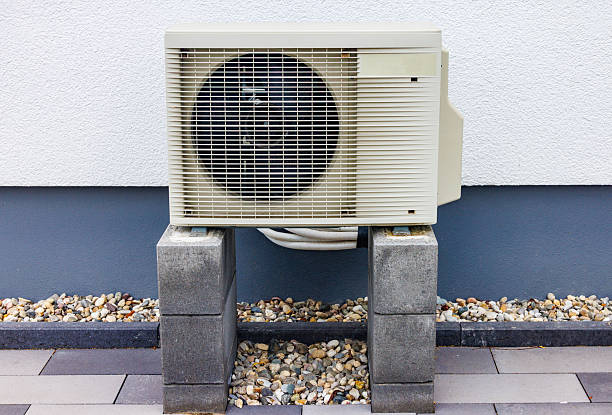 istock Heat pump standing on concrete blocks near building wall 2226381502