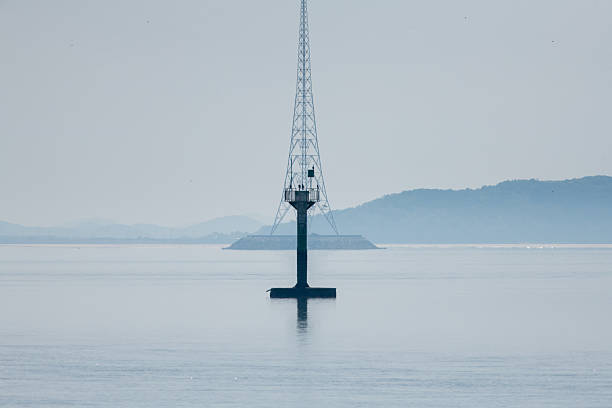 a lighthouse and a transmission tower over the sea.