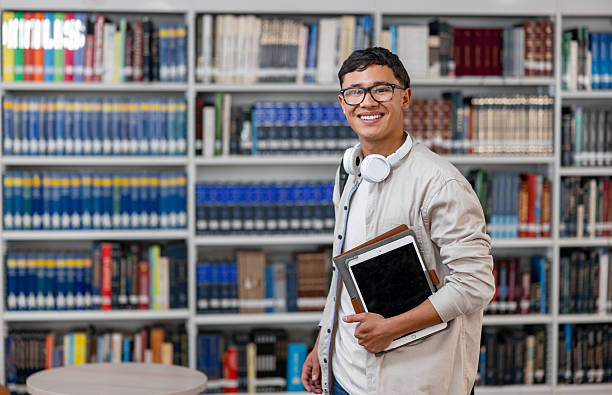 Portrait of a happy Latin American college student looking at the camera while smiling at the library