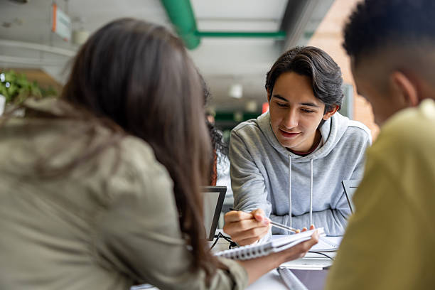 Latin American student explaining something to a friend while studying together at the library