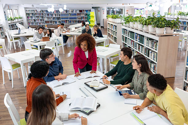 istock Professor tutoring a group of university students in the library 2226386009