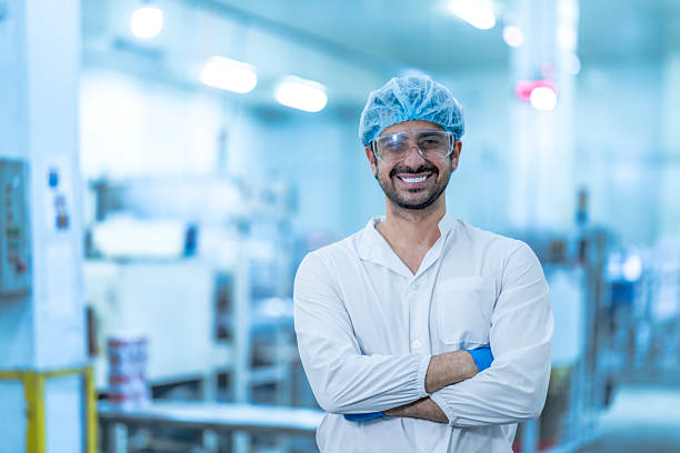 istock A confident food processing supervisor in protective gear, standing with arms crossed next to machinery in a factory, symbolizing leadership, quality assurance, and operational safety. 2226387305