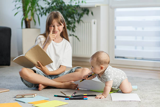 istock Big sister reading while baby chews on marker 2226388218