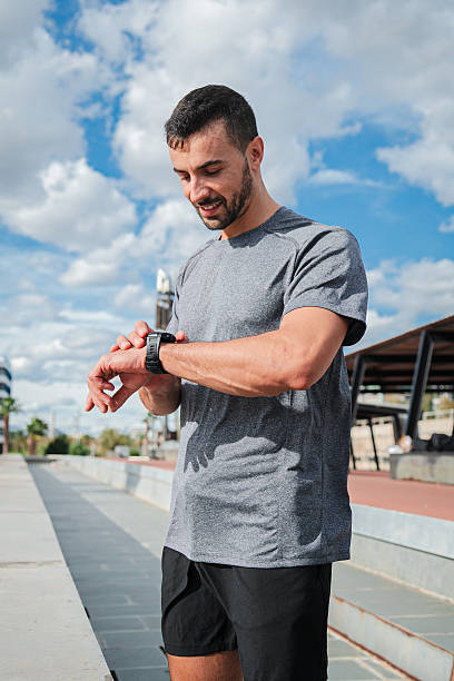 istock Vertical. Active Young Energetic Sports Man Checking His Progress on Smart Watch Gear During Outdoor Running Workout. Athletic Male Using Wristband To Achieve His Fitness Goals and Healthy Lifestyle 2226389500