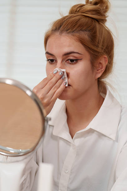 istock Woman gently cleanses her face using cotton pad while looking mirror, showcasing her commitment to skin health and beauty. This routine helps brighten her complexion and enhance her natural beauty 2226390579