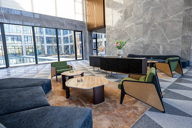 Unoccupied reception room with modern leather chairs and sofa, tables, floor lamp, rug, and access to outdoor terrace.