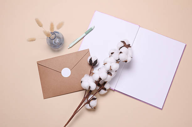 istock Open notebook or diary and envelope, cotton flower on beige background. Top view 2226400230