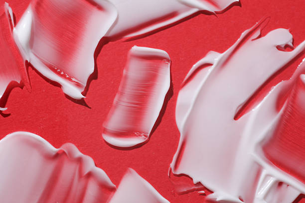 istock Shape and texture of white cream strokes on red background. Beauty concept 2226400347