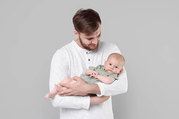 istock Father with his cute baby on grey background 2226403401
