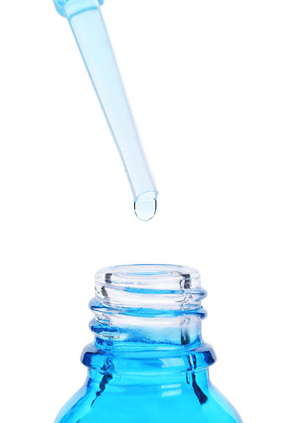 istock Dripping liquid from pipette into bottle isolated on white, closeup 2226404706