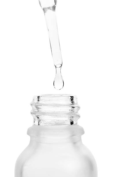 istock Dripping liquid from pipette into bottle isolated on white, closeup 2226404712