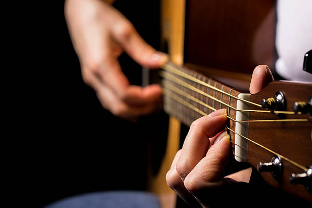 istock female hands playing guitar, black background. lifestyle, close-up. 2226404914