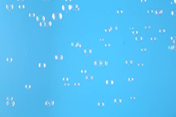 Beautiful transparent soap bubbles on light blue background