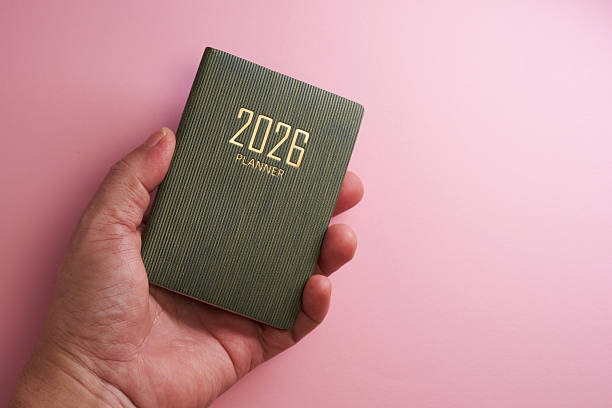 istock hand holding small 2026 planner against pink background 2226407576