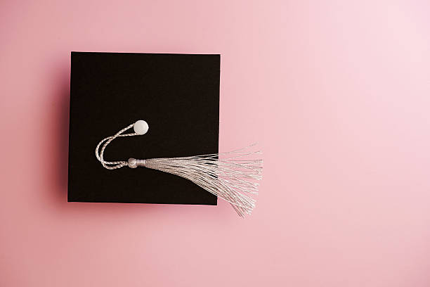 Top view of small mortarboard against pink background
