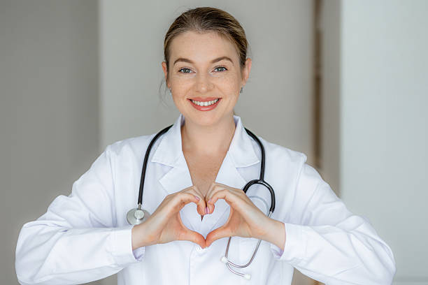 istock Smiling doctor making a heart shape with her hands wearing a white coat 2226412373