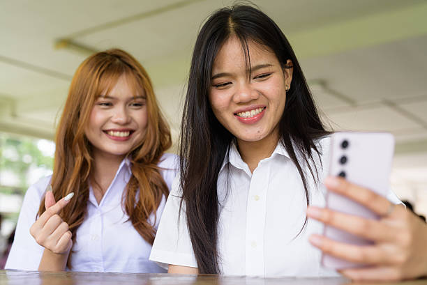 istock Young Thai University Students Relaxing Together at Campus Cafe Outdoors Taking Selfie Photo 2226415621