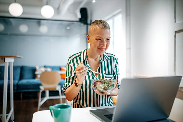 istock Woman working on laptop while having lunch in office cafeteria 2226416994