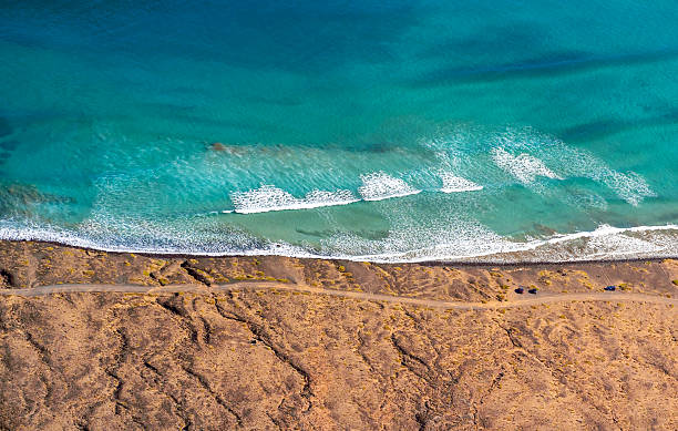 istock Blue ocean with waves and a sandy beach, top view. 2226417128