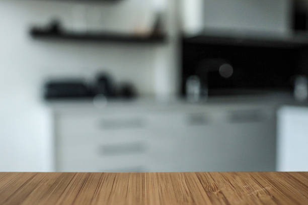 istock Wooden tabletop with blurred modern kitchen in the background. Minimalist design with black and white cabinetry, creating a clean and stylish home interior 2226419968