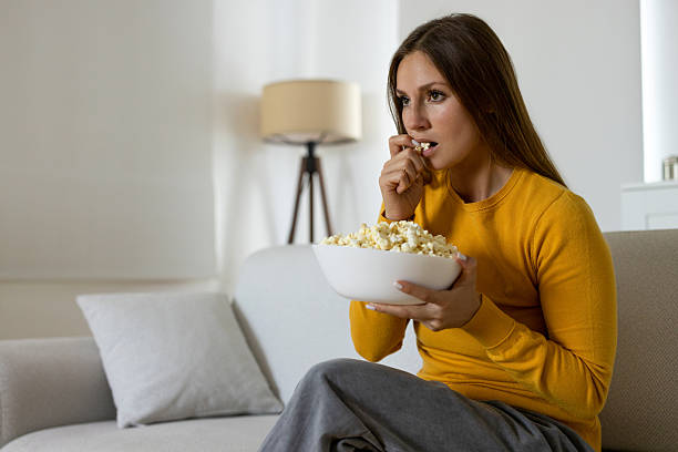 istock Woman eating popcorn while watching TV 2226420256