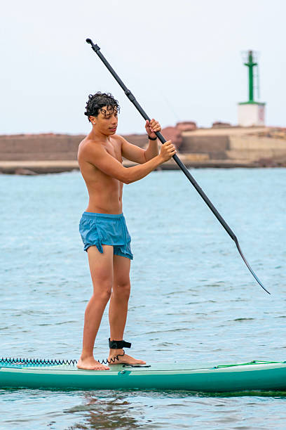 Teenager paddling on a stand-up paddleboard near the coast on a sunny summer day