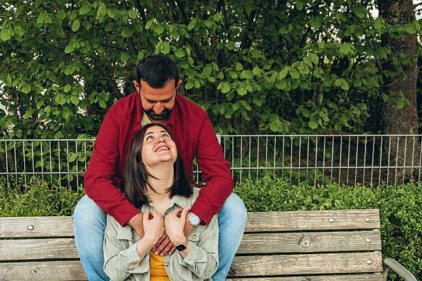 istock Happy couple sits on a bench outdoors, smiling and hugging each other. A joyful, affectionate moment capturing love, connection, and carefree togetherness in a relaxed, natural setting 2226421700