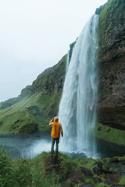 istock Man photographing Seljalandsfoss waterfall with smartphone in Iceland 2226422533