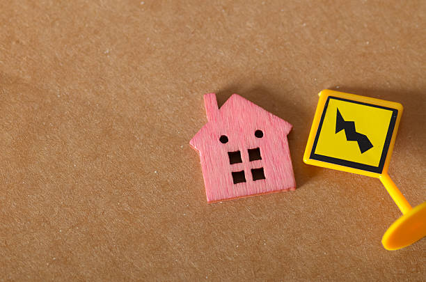 istock Tiny Pink House and Hazard Sign Symbolizing Real Estate Risk and Property Instability 2226424736