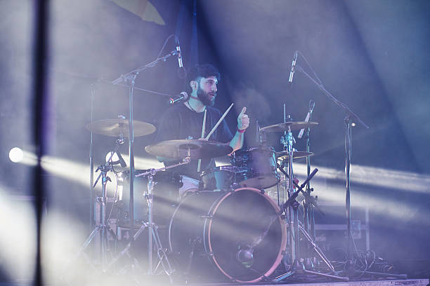 Drummer giving thumbs up while performing live on stage with drum kit