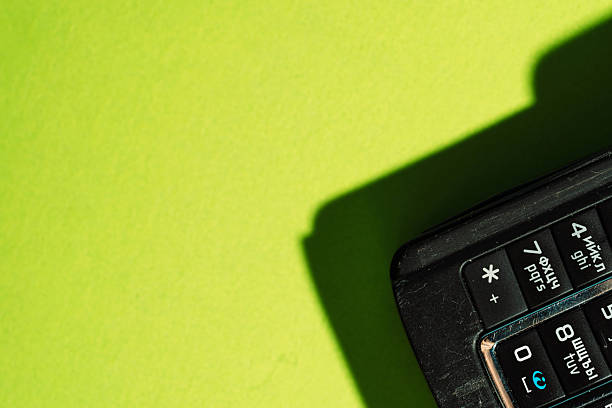 Close-up of retro mobile phone keypad on neon green background with sharp shadows. High quality photo