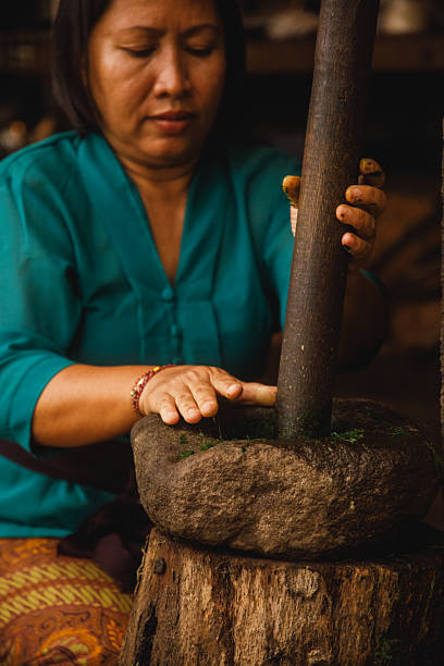 A close-up of a woman using a stone grinder, depicting traditional methods of crafting or food preparation. The earthy tones and focused composition emphasize the cultural and historical significance of such activities. This image captures the essence of traditions, craftsmanship, and manual skill passed down through generations.