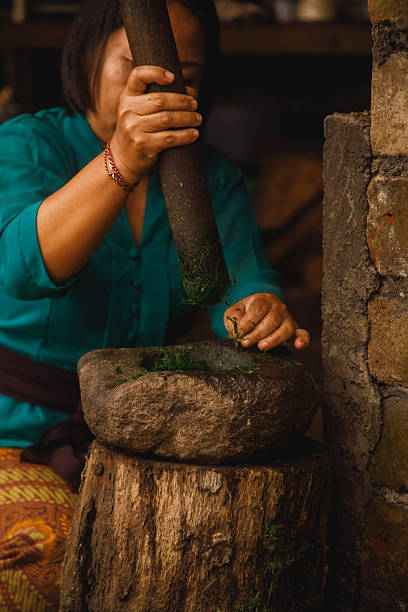 istock Woman Grinding Herbs with a Stone Mortar in a Rustic Setting 2226426769