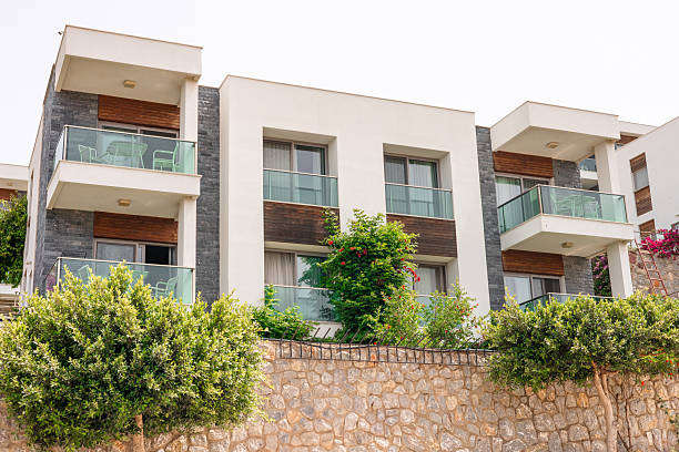 istock Modern apartment building with balconies and greenery. The structure features a stone wall and lush plants in front 2226427076