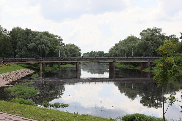 A breathtakingly picturesque view of a graceful bridge arching over a calm river, reflecting the serene landscape