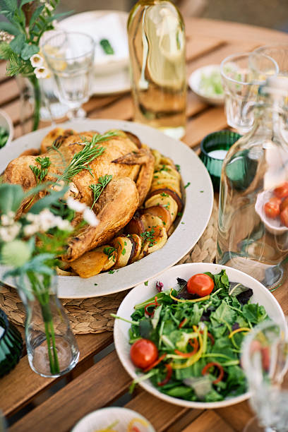 A beautifully arranged outdoor lunch scene featuring roast chicken, fresh salad, and summery table decor. Perfect for a relaxing meal in nature.