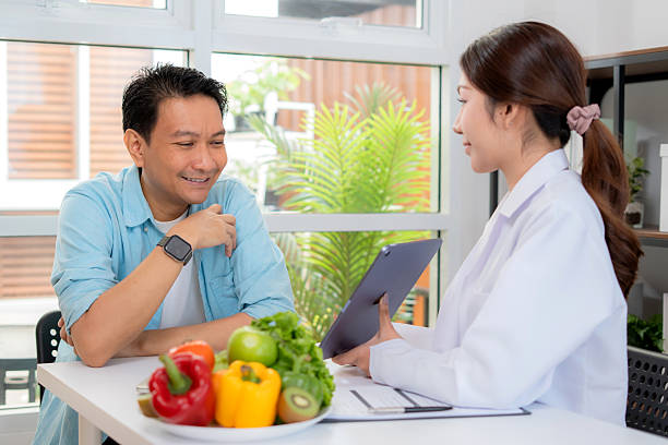 istock Asian nutritionist using tablet to explaining personalized meal plan with AI to patient during healthcare consultation, healthy lifestyle, woman dietitian showing nutrition plan with AI on tablet. 2226428739