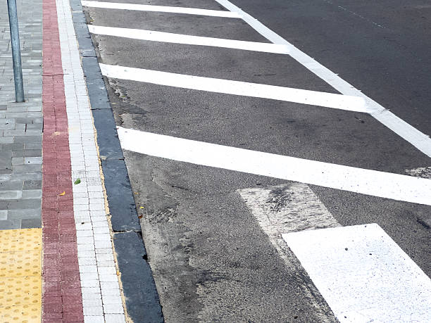 istock A clearly marked pedestrian crossing is visible alongside a textured sidewalk and road surface under bright sunlight in an urban area 2226432566