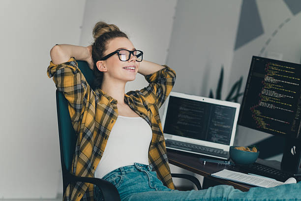 istock Young professional woman relaxing in a home office workspace with programming screens and a bright, casual style. 2226432758