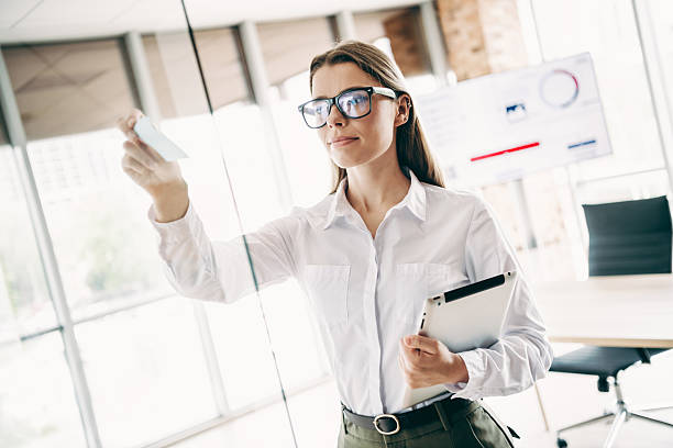 istock Confident businesswoman in a modern office writing on a glass board while holding a digital tablet 2226436548
