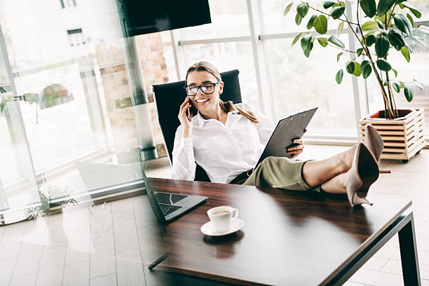 istock Confident businesswoman relaxing in office chair while multitasking with documents and phone in a modern workplace setting 2226436635