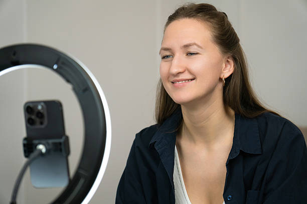 istock Young woman influencer is recording video content for social media using a ring light and smartphone, gesturing with her hands while sitting on a bed in her bedroom 2226437057