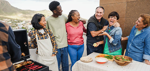 istock Multigenerational people doing barbecue at home's rooftop - Multiracial friends having fun eating and cooking together during weekend day - Summer and food concept - Main focus on african woman face 2226440077