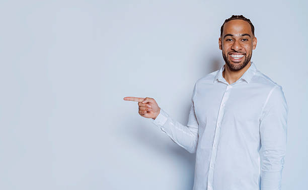 istock Smiling businessman pointing finger showing something on white background 2226443967