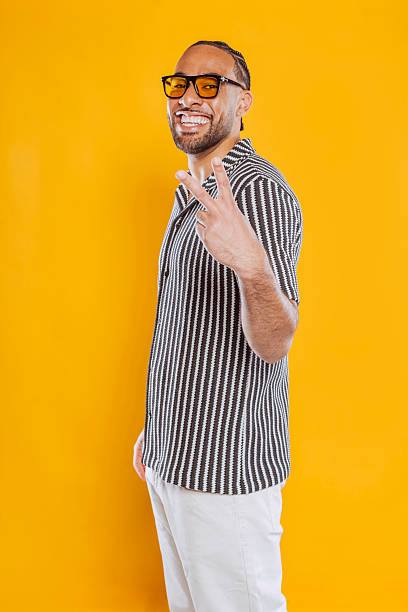 istock Smiling man showing victory sign on yellow background 2226443972