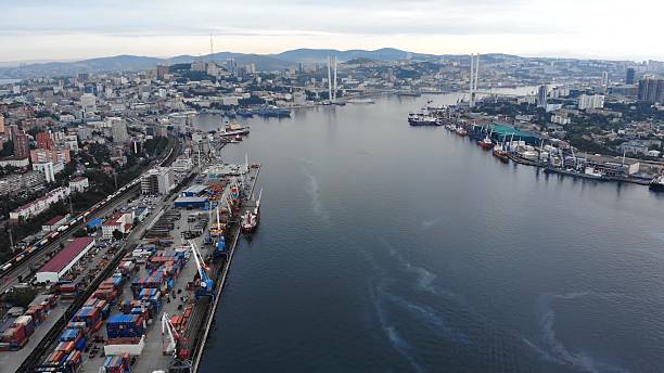 istock Cargo ships and bridges coexist in vladivostok harbor under a cloudy sky, creating a dynamic industrial seascape 2226445352