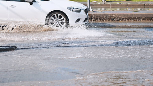 istock White car making splashes driving through flooded street after heavy rain, creating large puddles and water splashes 2226448283