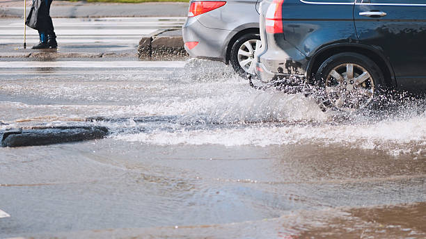 istock Vehicles navigating water covered urban roadway, spraying liquid during intense rainfall 2226449500
