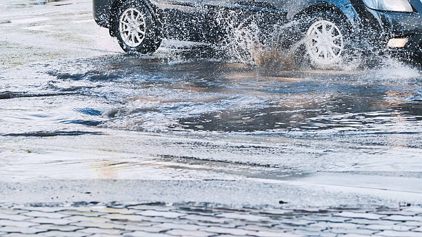 istock High speed vehicle splashing water while driving through roadside puddle, generating dramatic spray pattern 2226451219